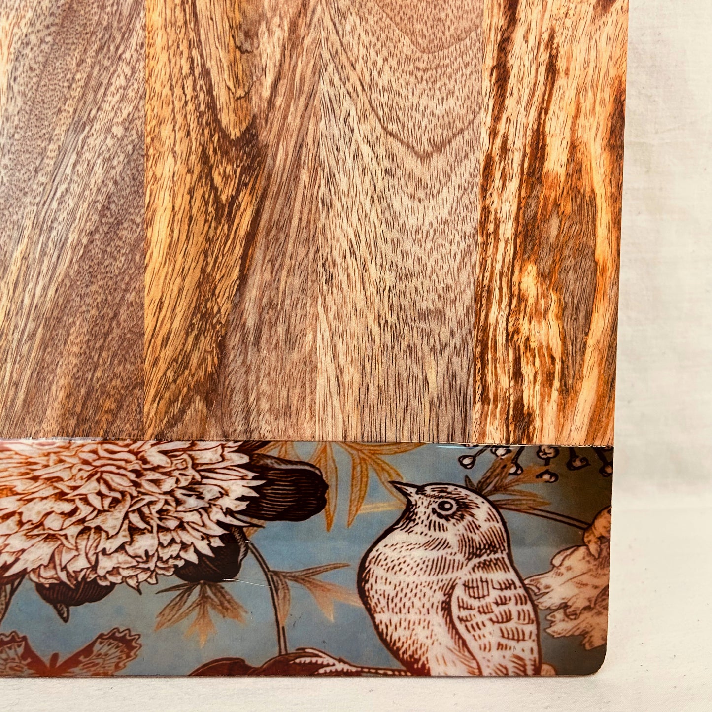 Close up of Mango Wood Cheese Board with handle. The Charcuterie Board has a nature, bird and flowers print at the bottom of the board.