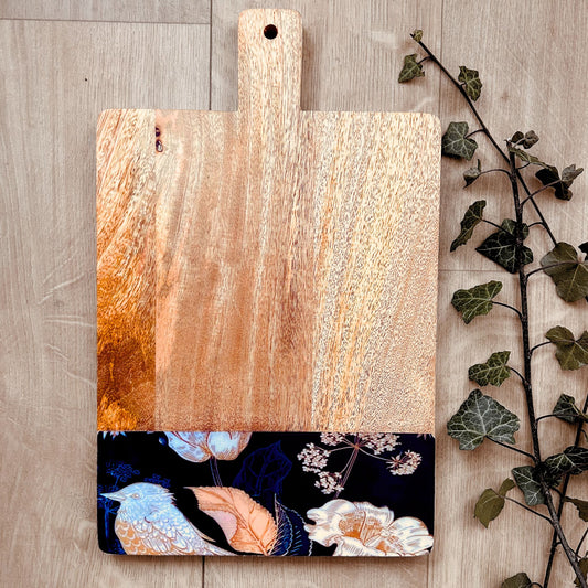 A cheese board with a nature inspired print of bird, leaves and flowers at the bottom as a border. 