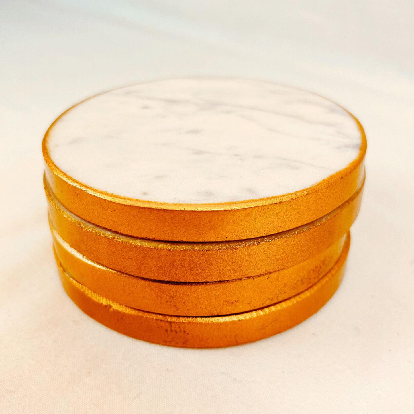 A stack of White round marble coasters with gold rim on a white background.