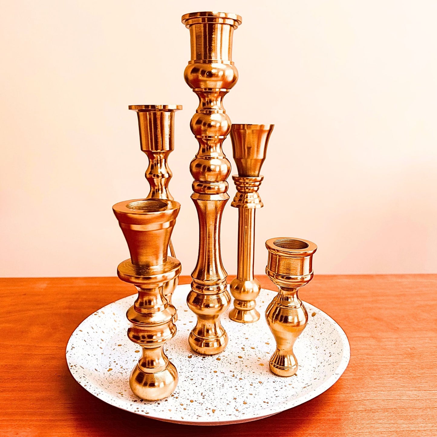 A 5 candle holder candelabra with a brass finish. The base is white with specks of gold on it.