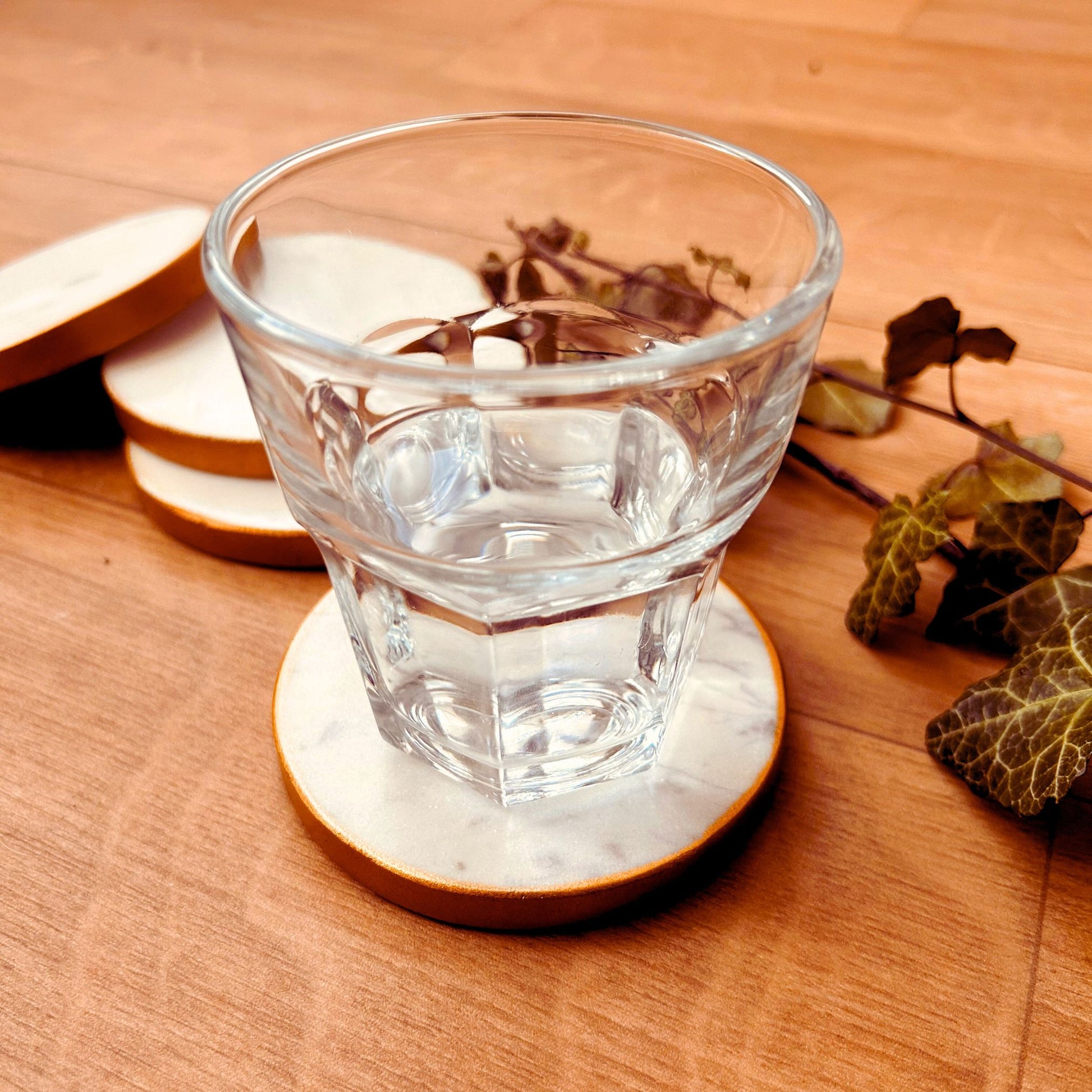 A glass kept on a white round marble coasters with gold rim.