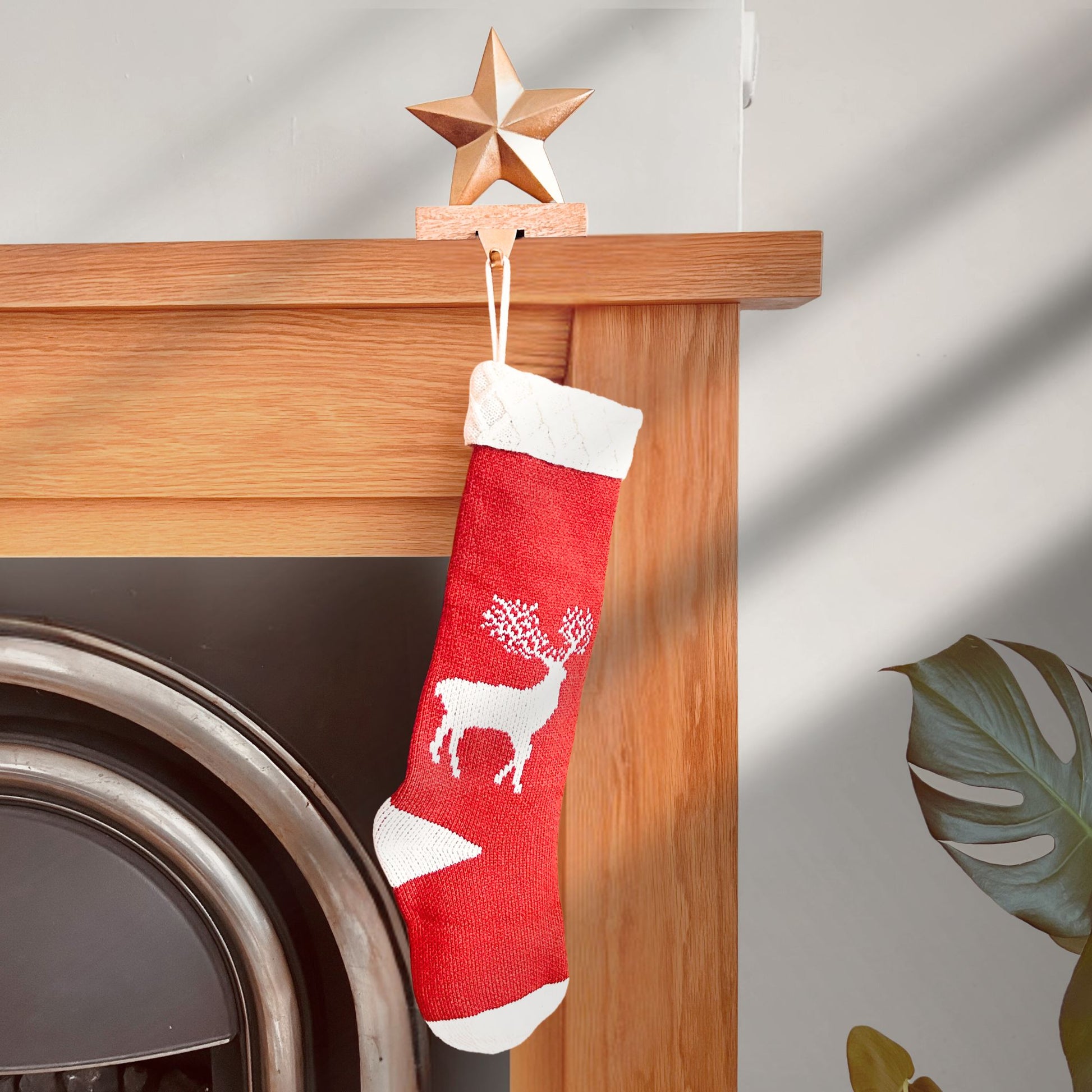 Brass Finish Star shaped stocking hanger on a wooden base kept on a mantle with a stocking hanging from it.