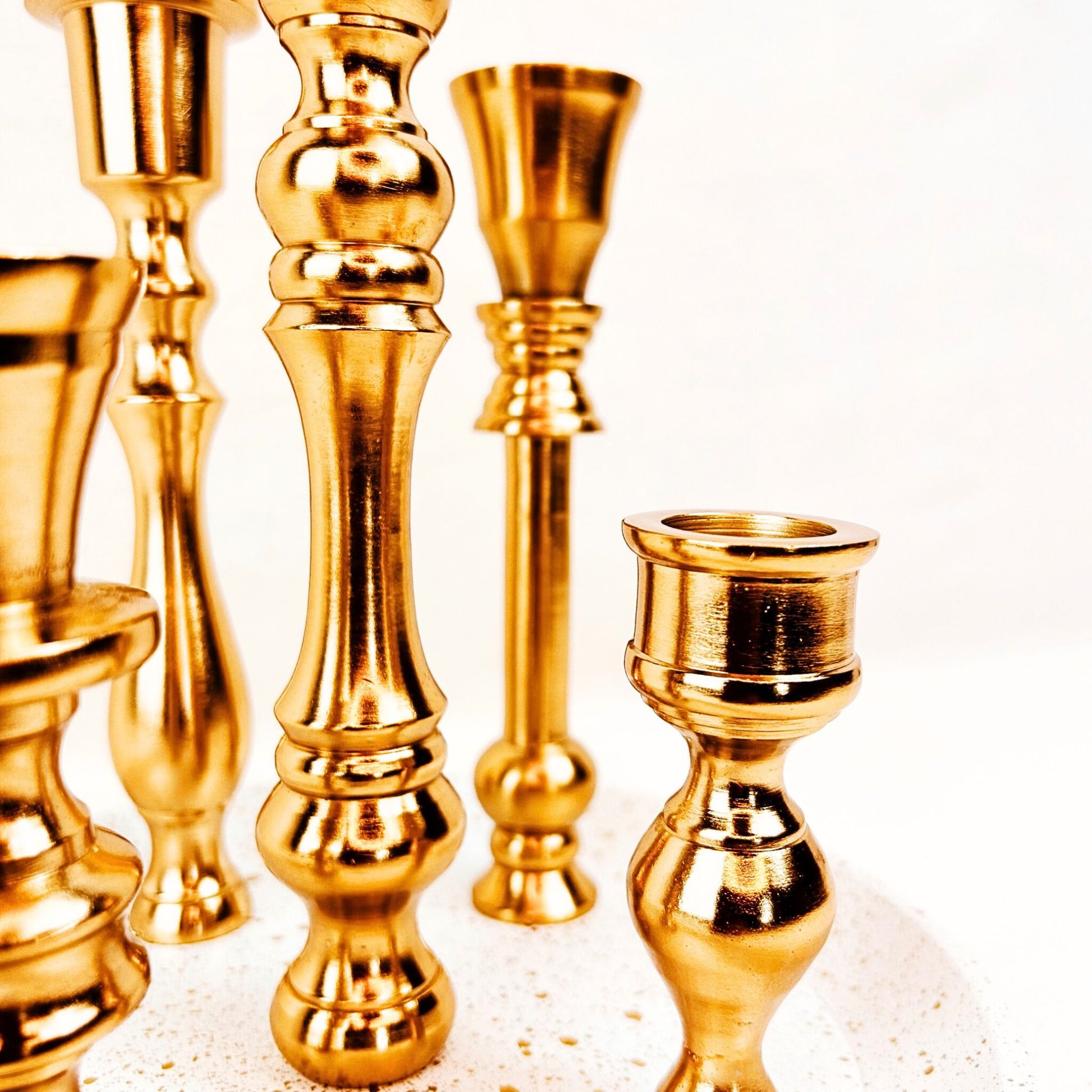 Close up of a 5 candle holder candelabra with a brass finish. The base is white with specks of gold on it.