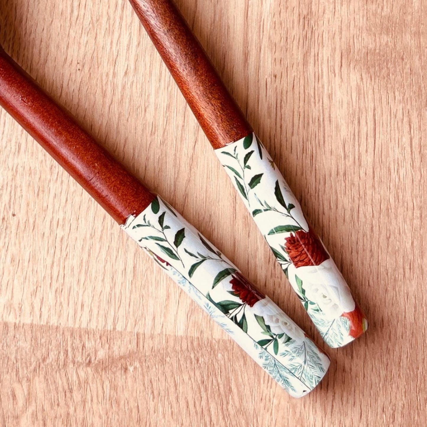 Close up of a pair of mango wood salad servers with nature print on the handle ends.