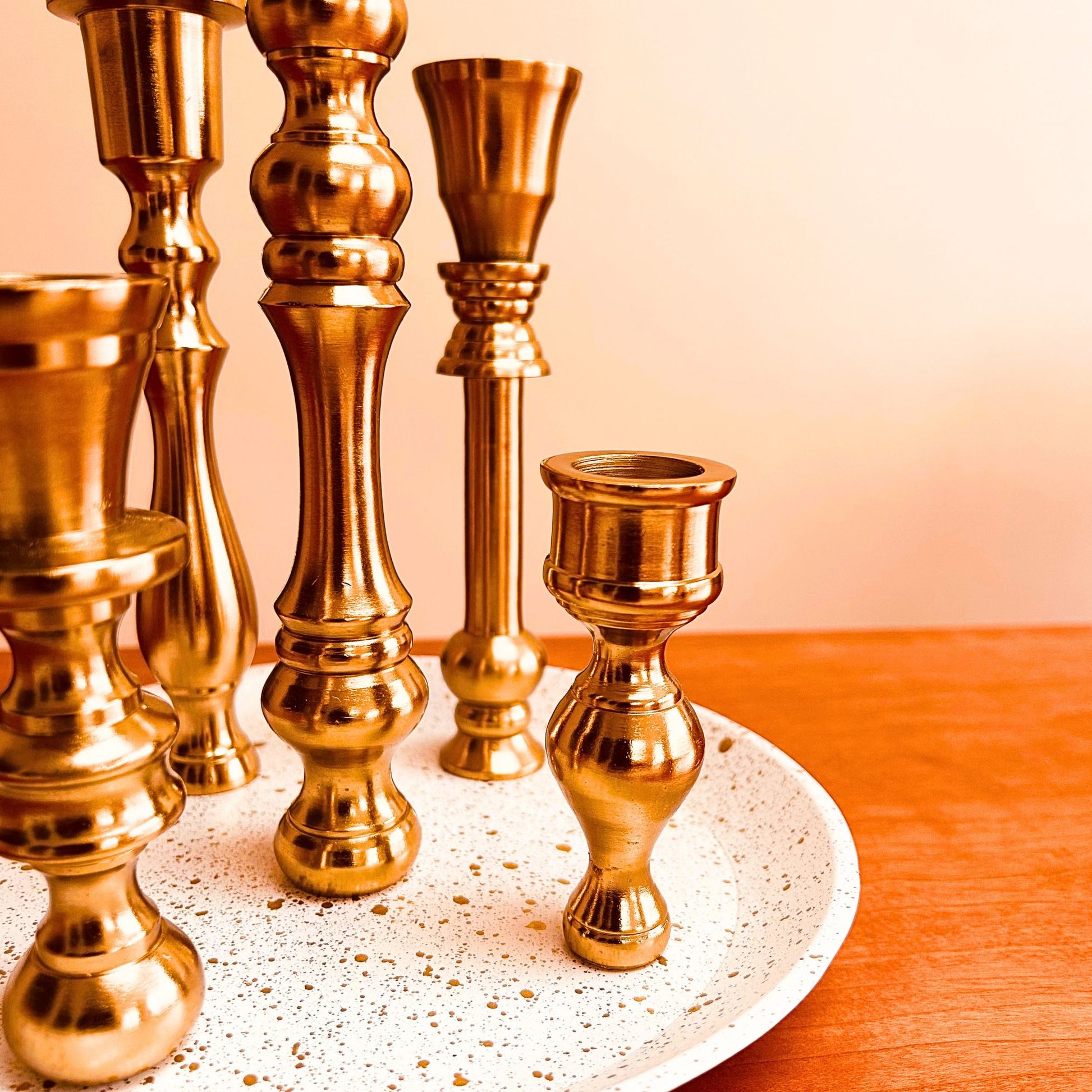 Close up of a 5 candle holder candelabra with a brass finish. The base is white with specks of gold on it.