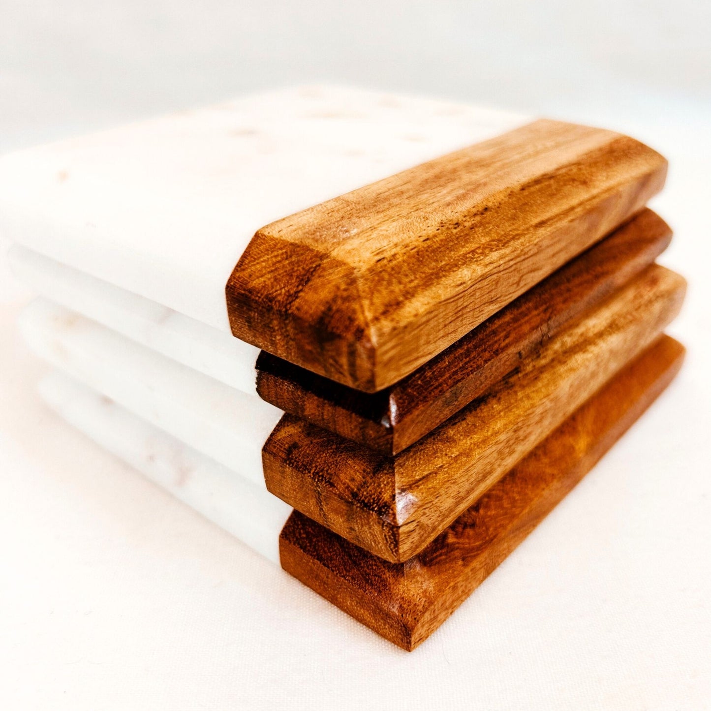 A stack of 4 Acacia and Marble Drink Coasters placed on top of each other.