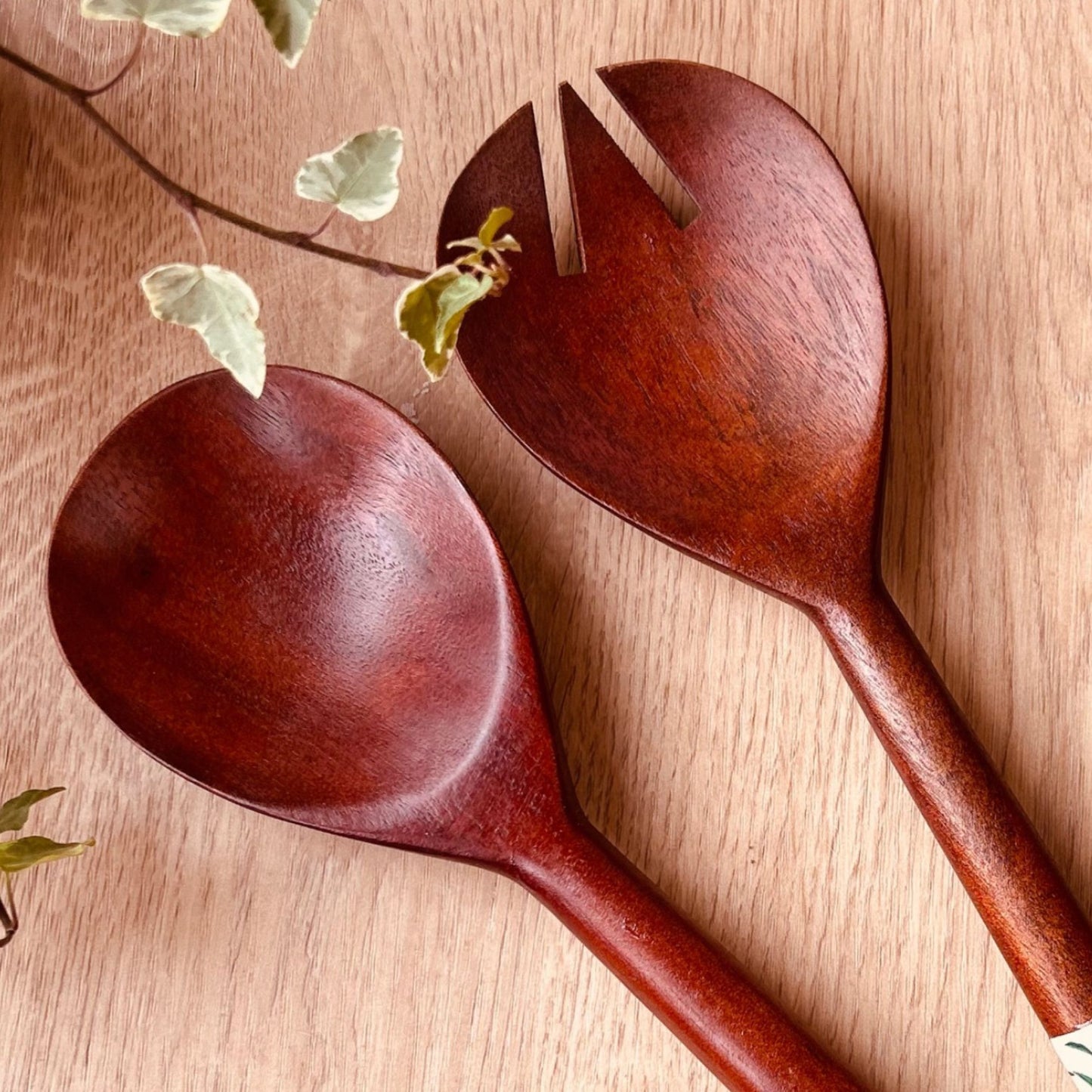 Close up of a pair of mango wood salad servers with nature print on the handle ends.