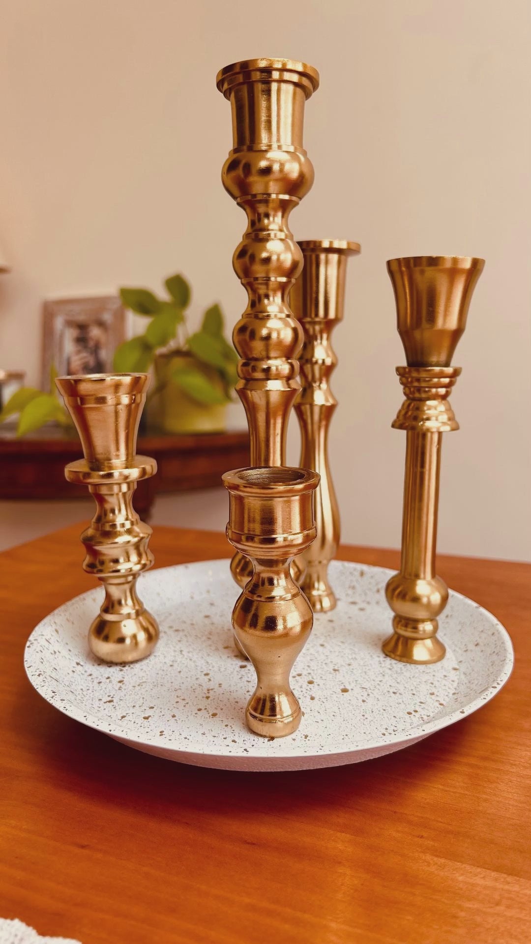 A product showcase of a 5 candle holder candelabra with a brass finish. The base is white with specks of gold on it.